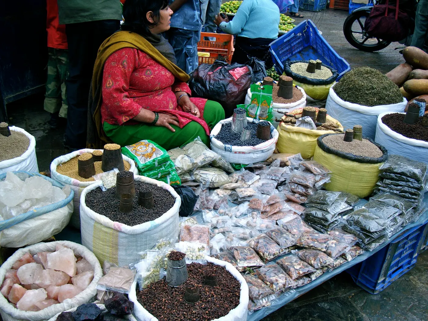 Nepali spice market - display of commonly used spices - cumin, coriander, fenugreek seeds, black pepper, pink Himalayan salt, packaged spices, turmeric, red and green chilies, garlic and fresh ginger, and onions.