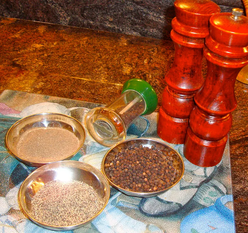 Crushed black pepper with the use of pepper mill (everyday kitchen gadget), whole black pepper and finely ground pepper