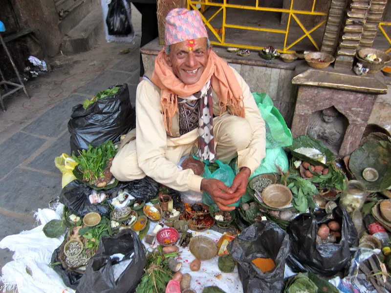 Smiling Hindu priest is surrounded by gifts (daan) placed in the saal leaves given by devotee during the religious festival of Maghe Sankranti in Nepal.