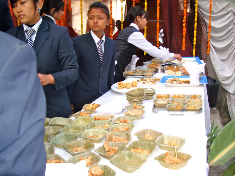 Food items are being placed in the leaf plates during the feast.