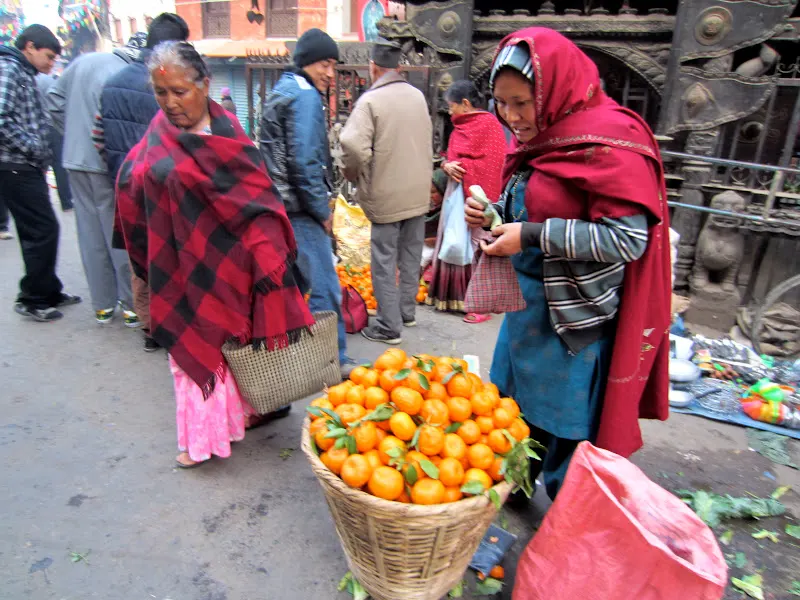 A road-side vendor attends to a clients and counts her change.