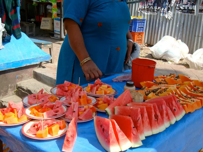 A fresh fruit seller is waiting for customers in a busy open market - fresh watermelon and papaya.