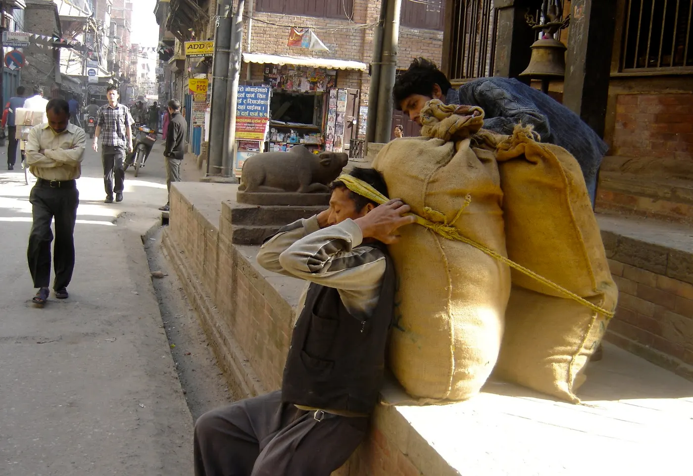 Nepali Porter's burlap sack is filled with rice - he is trying to transport to a different location----Oops it is so heavy!