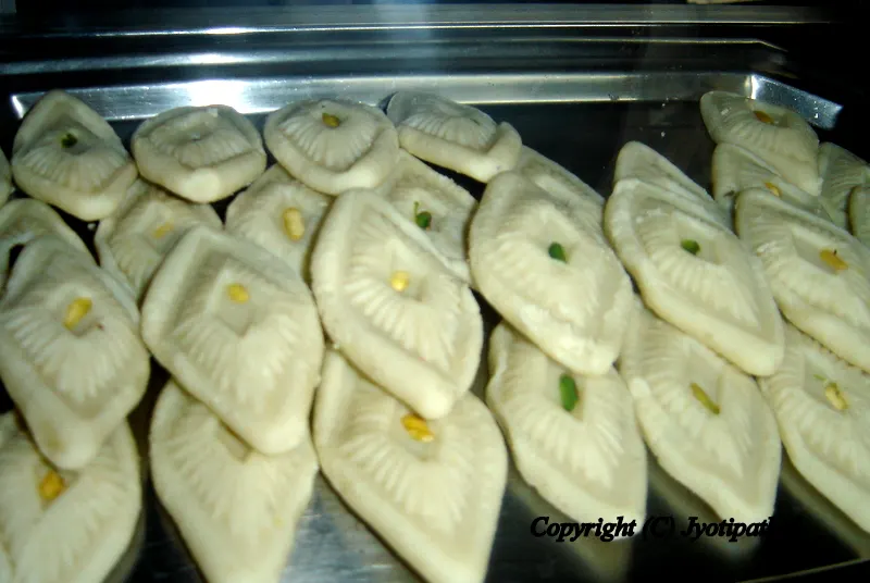 Pure Kaaju Peda - काजु पेडा - a decorative, rich and delicious variation of Peda made with ground cashew nuts, thickened milk, sugar and studded with finely sliced pistachio and crushed green cardamom.