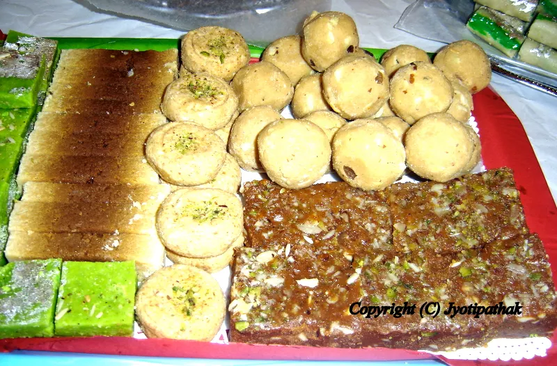 Above (L top) Milk Cake, Round Milk Peda (दूध को पेडा), Besan ko Laddu (बेसन को लड्डु), and the bottom is Gud-Paak (गुडपाक) which is a traditional Nepali sweet made from flour, edible gum, brown sugar and assorted mixed nuts and flavorings.