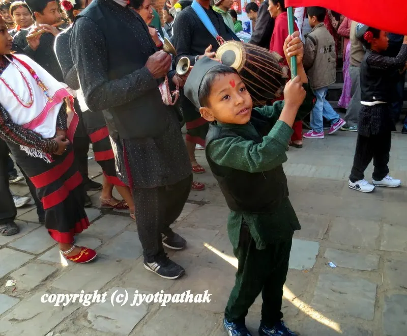 A cheerful Nepali boy carrying a flag during a religious procession